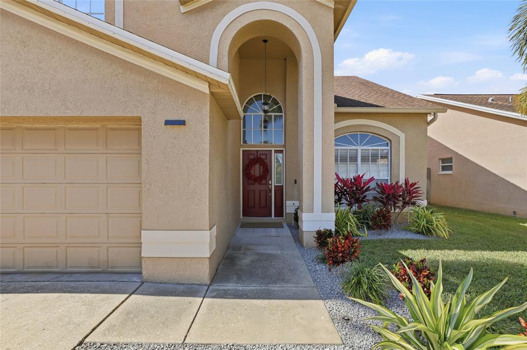 The exterior of a tan stucco house features a recessed front entrance and a garage — 11235 CLAYRIDGE DRIVE, TAMPA, FL