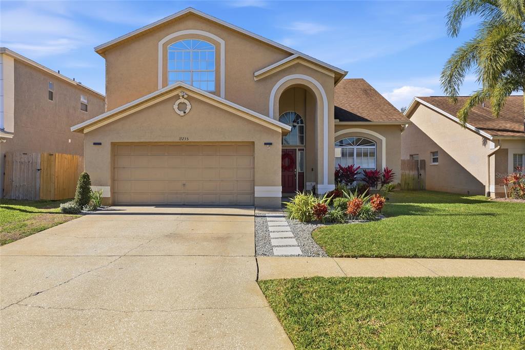 A two-story suburban house with a tan stucco exterior, a two-car garage, and a driveway — 11235 CLAYRIDGE DRIVE, TAMPA, FL