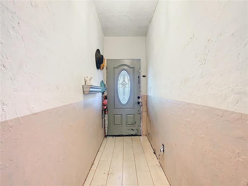 A narrow entryway features light-colored wood-look flooring, two-toned walls, and a gray front door — 900 N 30TH STREET, HAINES CITY, FL