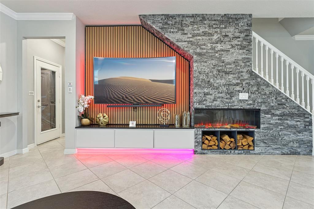 A living room features a wall-mounted television, wood slat paneling, stone fireplace, and LED lighting — 16205 SAINT KITTS CIRCLE, CLERMONT, FL