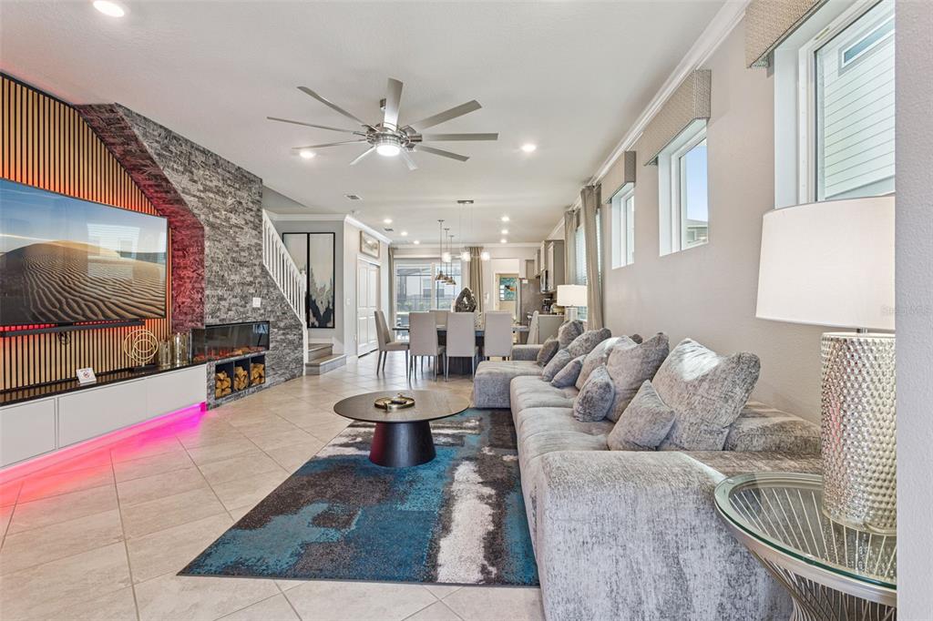 A living room features a stone fireplace wall, a large sectional sofa, and tile flooring — 16205 SAINT KITTS CIRCLE, CLERMONT, FL