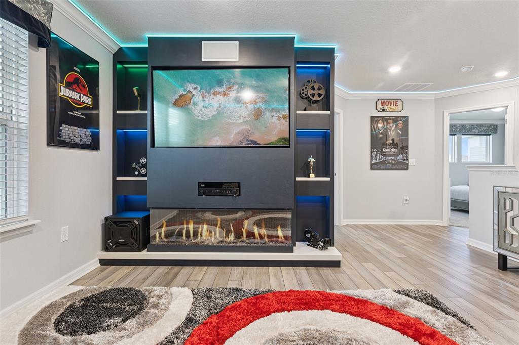A media room features a built-in entertainment center with a fireplace, television, and accent lighting — 16205 SAINT KITTS CIRCLE, CLERMONT, FL