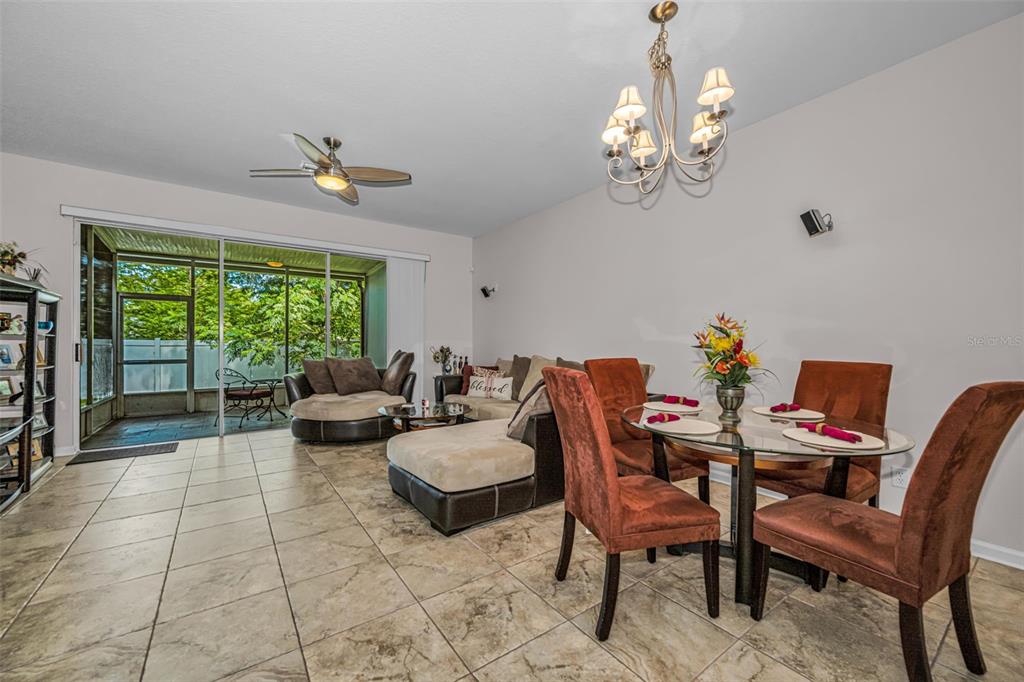 A living and dining area with tile floors, a ceiling fan, and a screened-in patio — 8414 SANDY BEACH STREET, TAMPA, FL