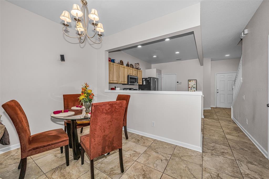 A dining area with a glass table and chairs sits adjacent to an open kitchen — 8414 SANDY BEACH STREET, TAMPA, FL