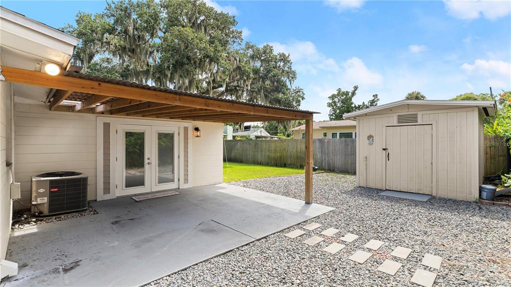 A concrete patio with a wooden pergola sits beside a house and a storage shed — 358 S ORCHARD STREET, ORMOND BEACH, FL