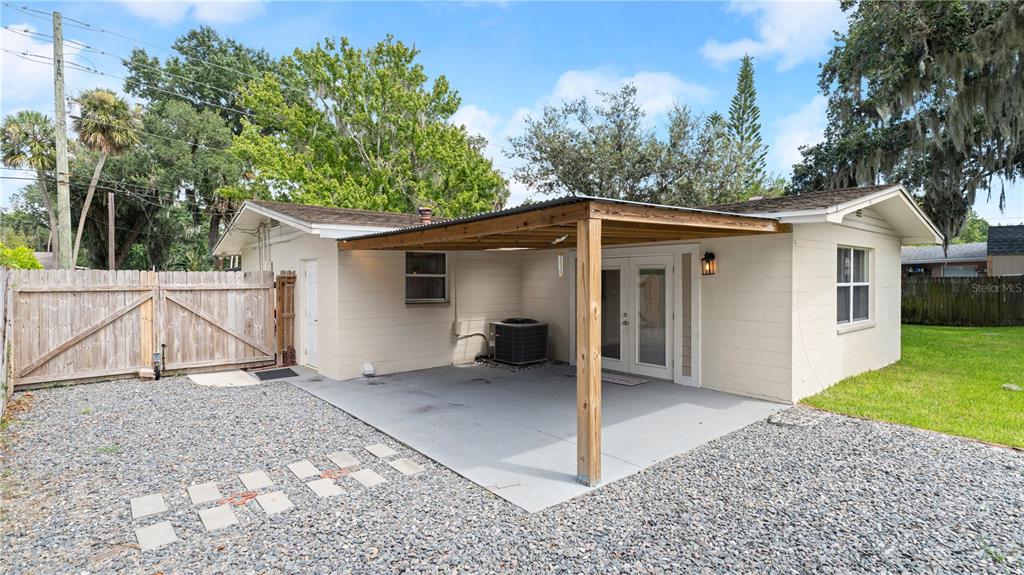 The exterior of a house features a covered concrete patio, gravel yard, and wooden fence — 358 S ORCHARD STREET, ORMOND BEACH, FL