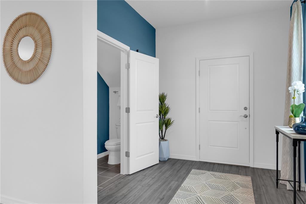 A hallway features gray wood-look flooring, a white door, and an open doorway to a bathroom — 907 CASTLEFORD AVENUE, PALM BAY, FL