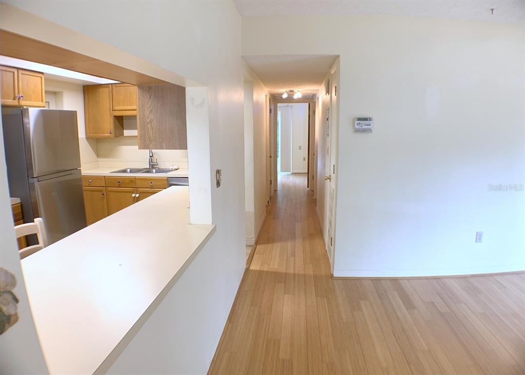 A kitchen with wood cabinets and stainless steel appliances overlooks a hallway with wood flooring — 2814 W PRICE AVENUE, TAMPA, FL