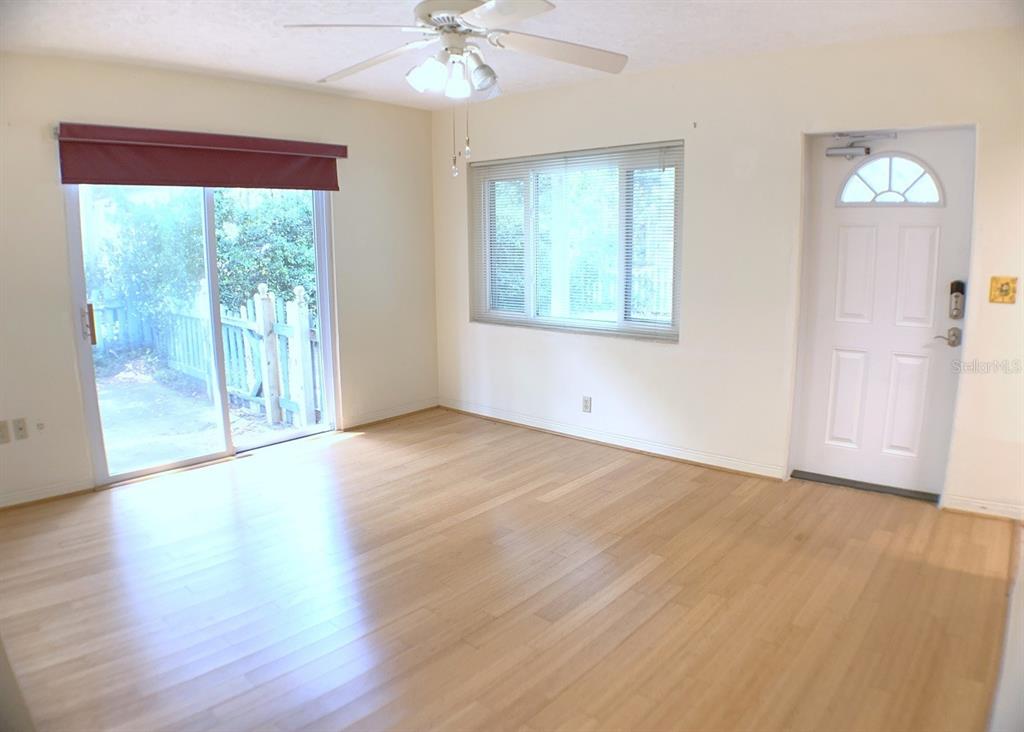 An empty room features light wood flooring, a ceiling fan, sliding glass doors, and windows — 2814 W PRICE AVENUE, TAMPA, FL