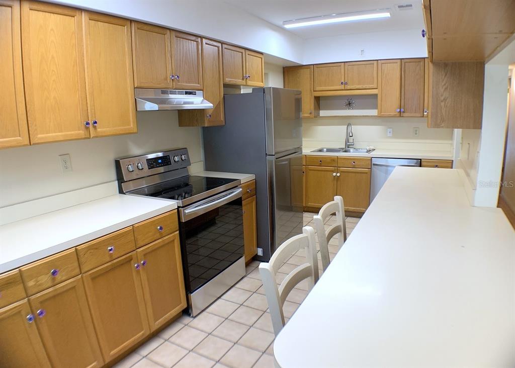 A kitchen features oak cabinets, stainless steel appliances, a breakfast bar, and tile flooring — 2814 W PRICE AVENUE, TAMPA, FL