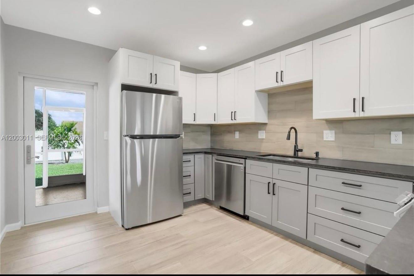 A kitchen features white upper cabinets, grey lower cabinets, stainless steel appliances, and wood flooring — 2550 N Dixie Hwy # 2570, Boca Raton FL 33431, BOCA RATON, FL