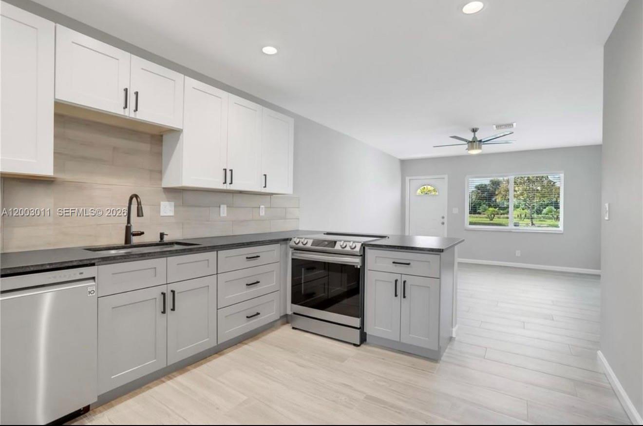 A kitchen with white upper cabinets, gray lower cabinets, stainless steel appliances, and wood-look flooring — 2550 N Dixie Hwy # 2570, Boca Raton FL 33431, BOCA RATON, FL