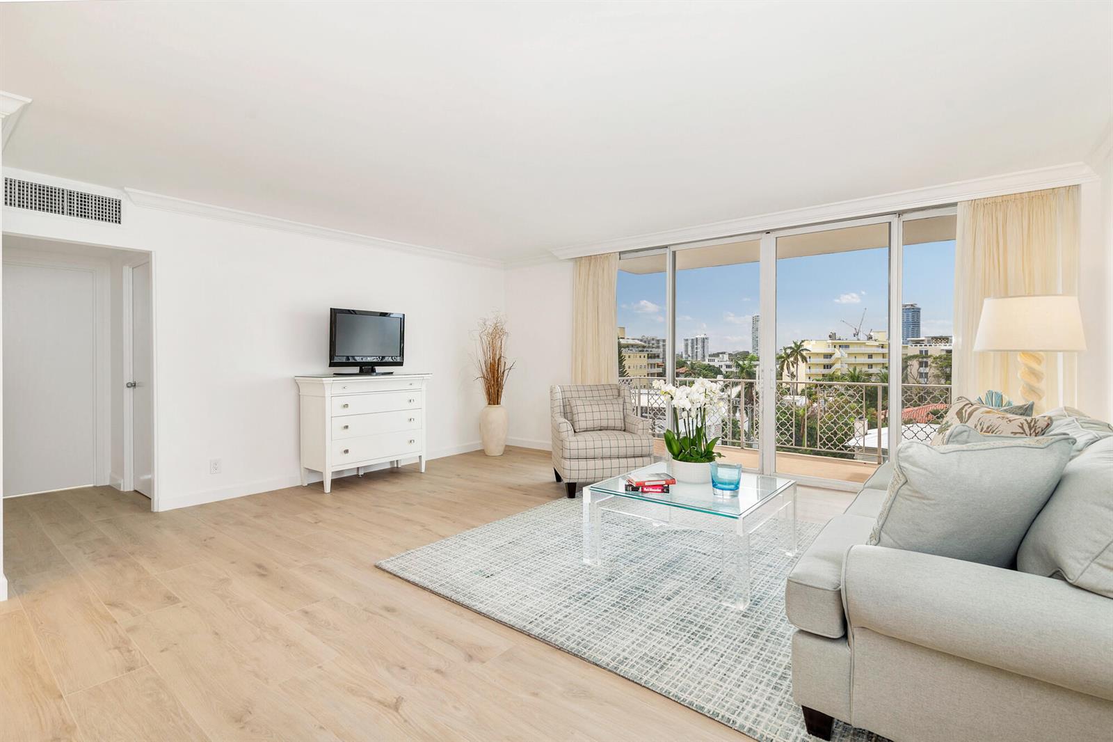 A living room with light wood floors, a glass coffee table, and a balcony view — 354 Chilean Avenue # 6c, Palm Beach FL 33480, PALM BEACH, FL