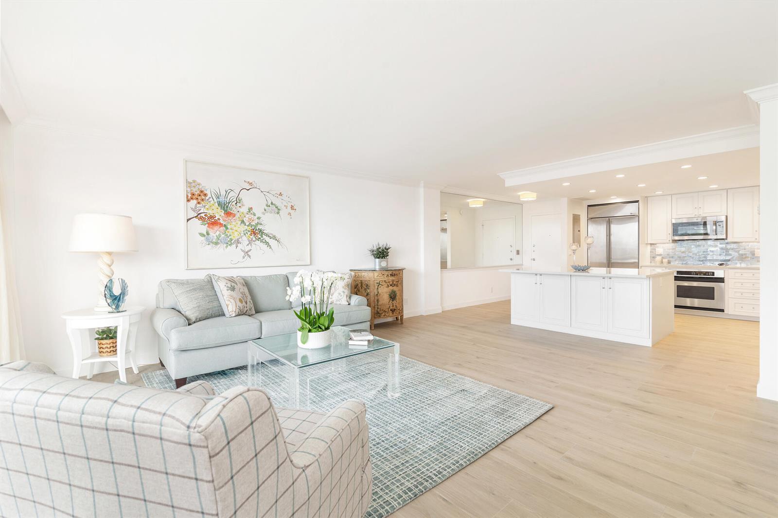 A bright open-concept living room and kitchen featuring light wood floors and white cabinetry — 354 Chilean Avenue # 6c, Palm Beach FL 33480, PALM BEACH, FL