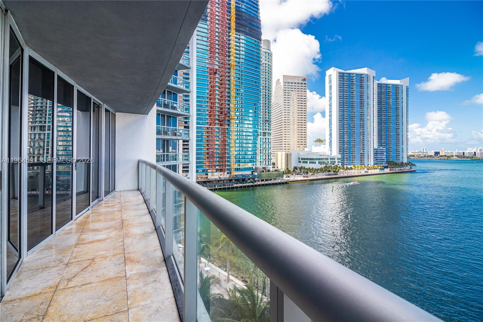 A balcony with tile flooring overlooks a waterfront cityscape with high-rise buildings — 465 Brickell Ave # 917, Miami FL 33131, MIAMI, FL