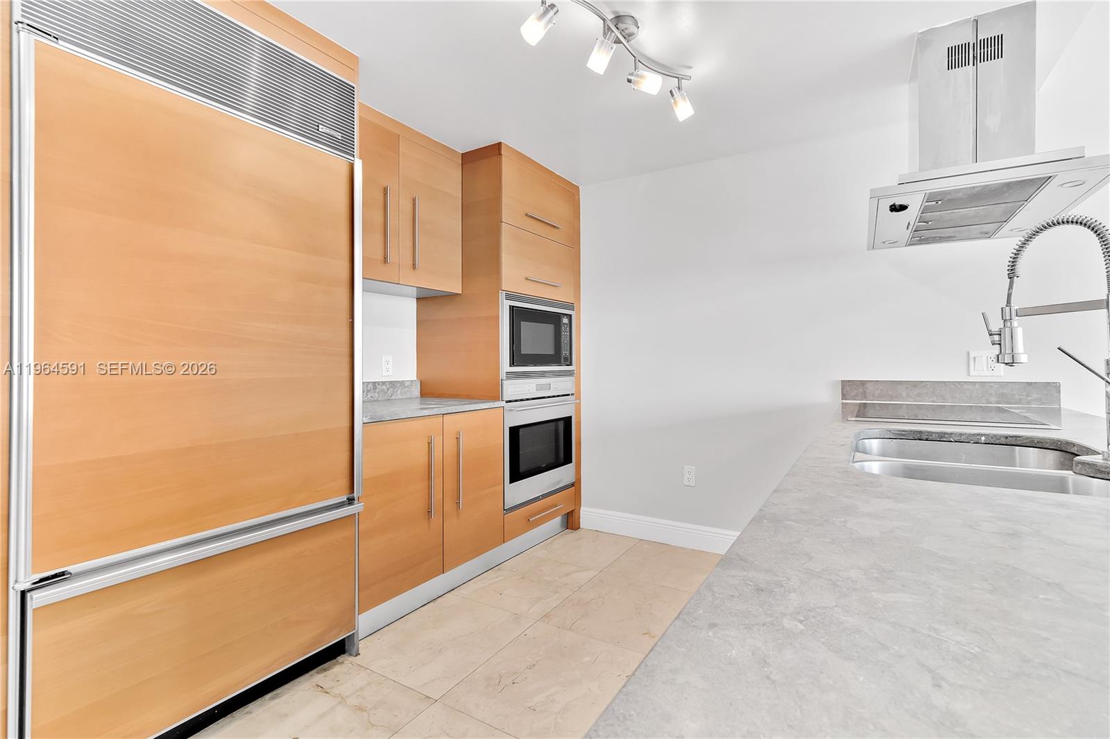 A modern kitchen features light wood cabinetry, stainless steel appliances, and gray stone countertops — 465 Brickell Ave # 917, Miami FL 33131, MIAMI, FL