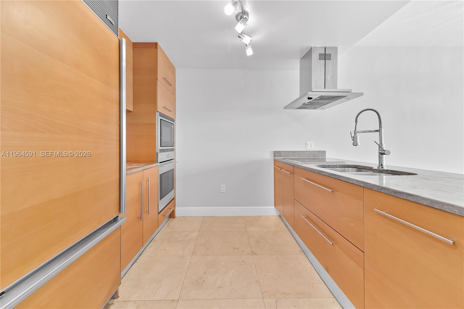 A galley kitchen features light wood cabinets, stainless steel appliances, and gray stone countertops — 465 Brickell Ave # 917, Miami FL 33131, MIAMI, FL