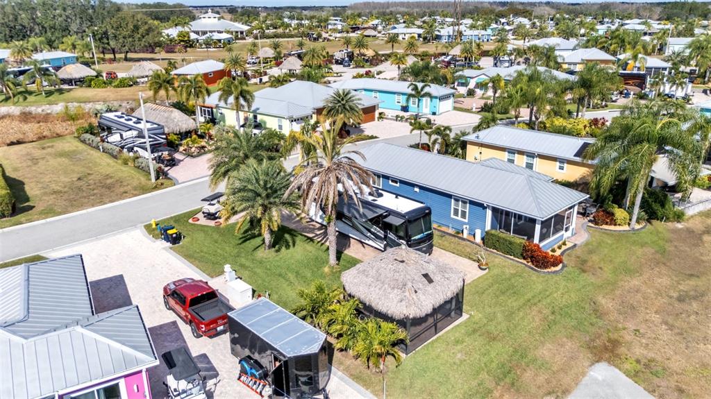 An aerial view shows a blue house with a metal roof, a motorhome, and a tiki hut — 3272 FISH HAWK DRIVE, POLK CITY, FL