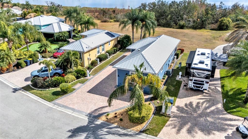 An aerial view shows two houses with metal roofs, paved driveways, and a parked RV — 3272 FISH HAWK DRIVE, POLK CITY, FL