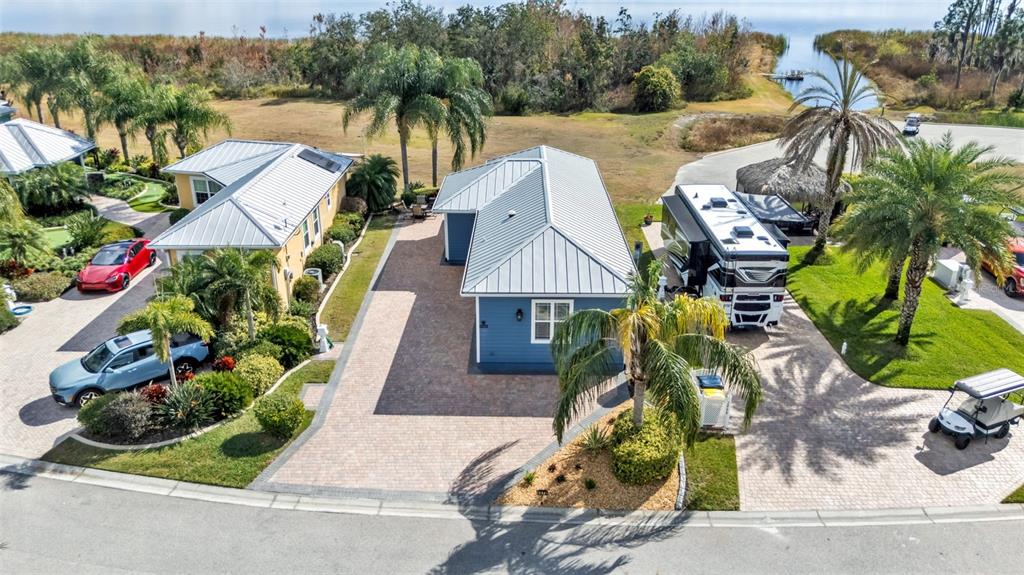 An aerial view shows two houses with metal roofs, paved driveways, and a parked RV — 3272 FISH HAWK DRIVE, POLK CITY, FL
