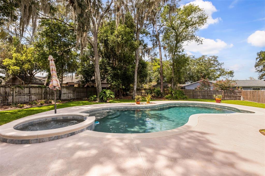 A backyard swimming pool with an attached hot tub and a wooden privacy fence — 260 QUEENSBERRY COURT, LONGWOOD, FL