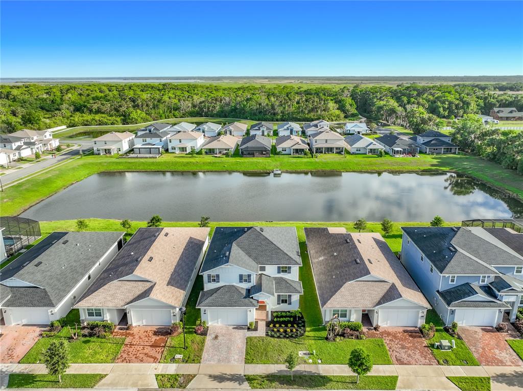 An aerial view shows a row of suburban houses facing a pond and wooded area — 3392 BLUFF OAK LANE, SANFORD, FL