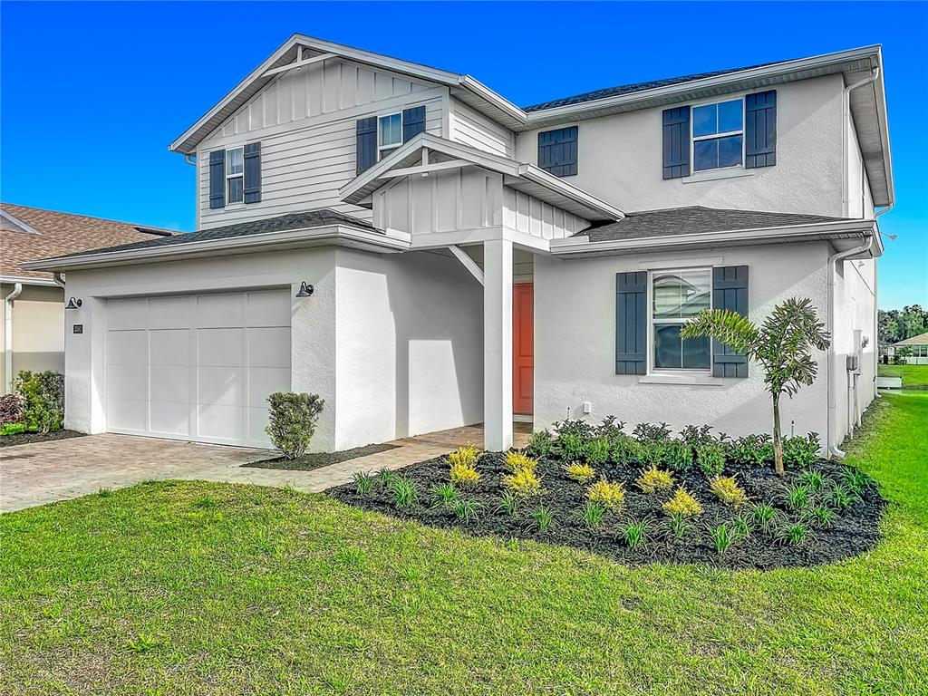A two-story house with a white stucco facade, a garage, and a small front garden — 3392 BLUFF OAK LANE, SANFORD, FL