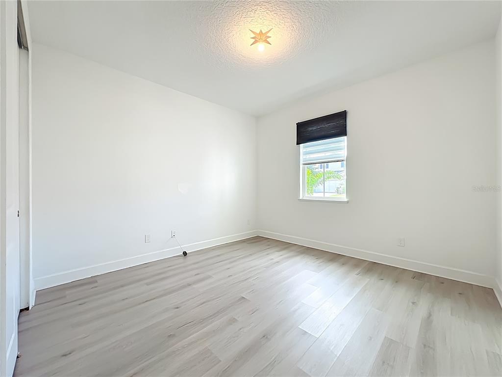 An empty bedroom features white walls, light wood-look flooring, and a single window — 3392 BLUFF OAK LANE, SANFORD, FL