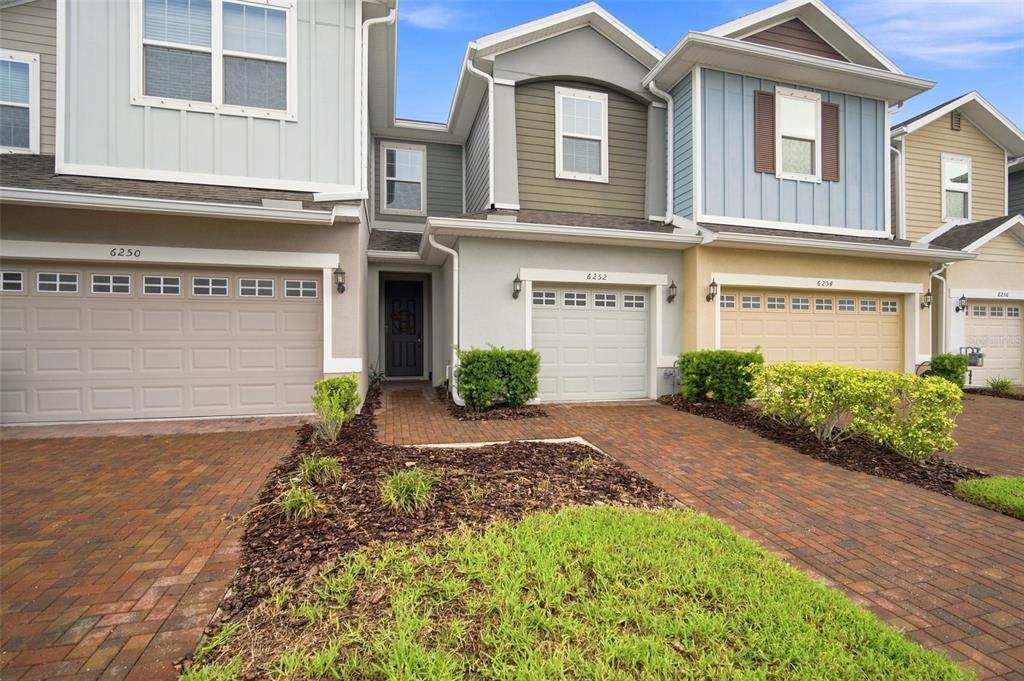 The exterior of a row of multi-story townhouses features brick driveways and attached garages — 6252 CAMINO DRIVE, APOLLO BEACH, FL