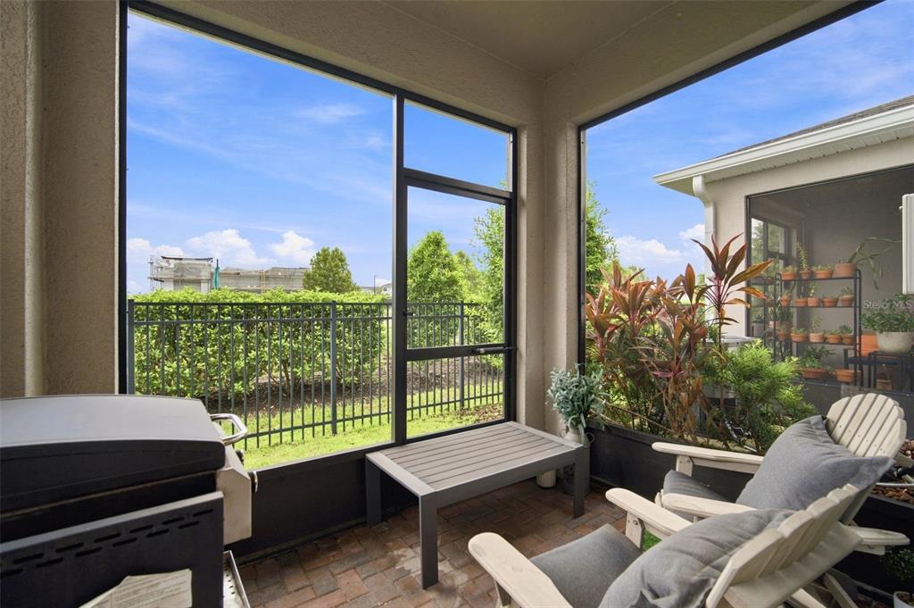 A screened-in patio features brick flooring, a grill, seating, and a view of a fence — 6252 CAMINO DRIVE, APOLLO BEACH, FL