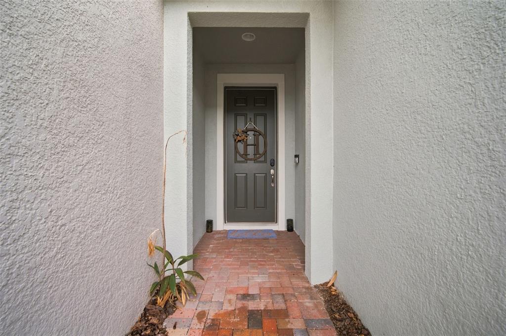A brick walkway leads to a dark gray front door with a wreath in a recessed entryway — 6252 CAMINO DRIVE, APOLLO BEACH, FL