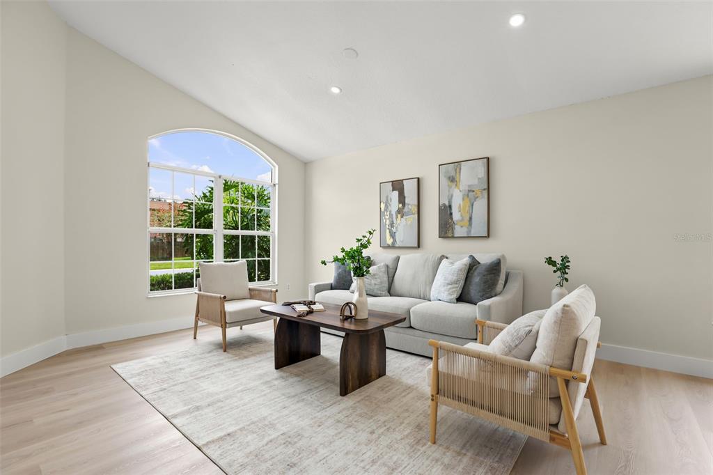 A living room features a light gray sofa, two armchairs, a wooden coffee table, and an arched window — 638 TALL OAKS TERRACE, LONGWOOD, FL