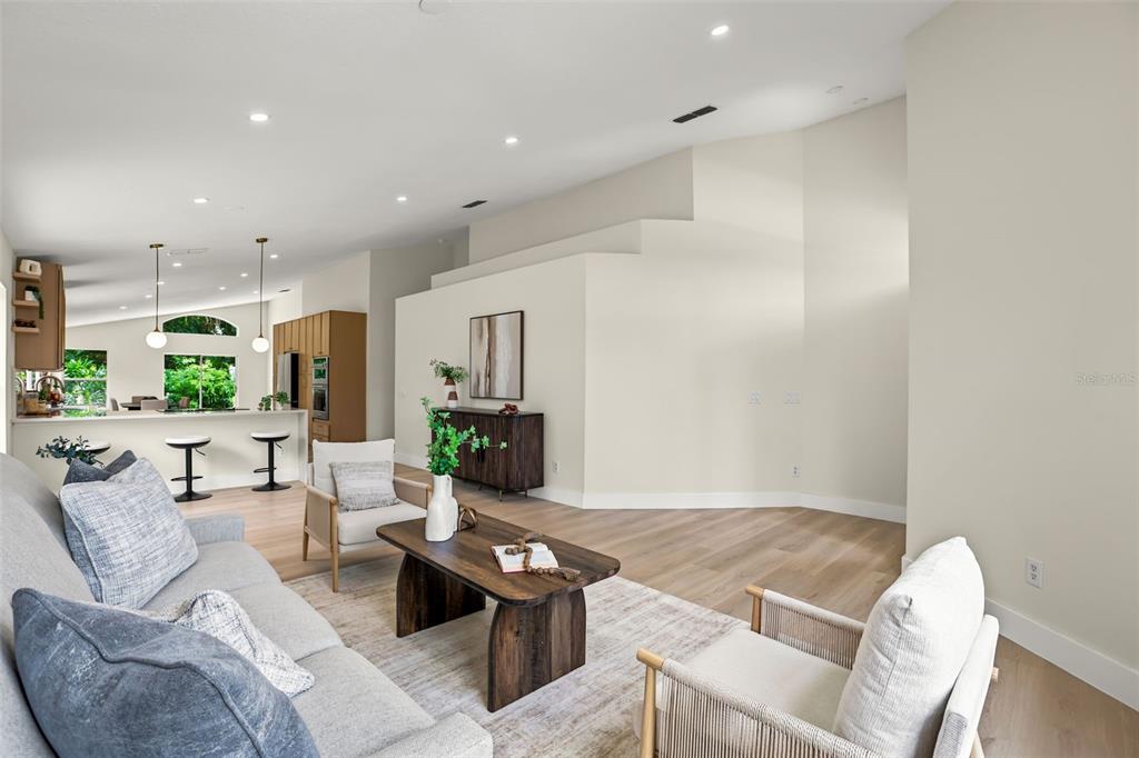 A living room with light wood floors, a gray sofa, and a tiered accent wall — 638 TALL OAKS TERRACE, LONGWOOD, FL