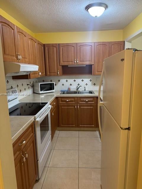 A kitchen features wood cabinets, a white refrigerator, a stove, and light-colored tile flooring — 9301 SW 92nd Ave # 210C, Miami FL 33176, MIAMI, FL