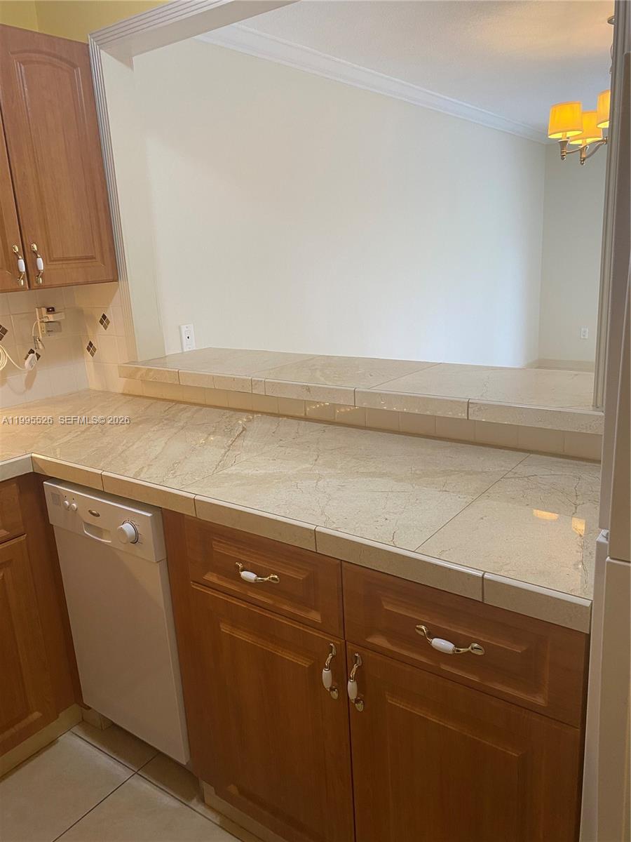 A kitchen features wood cabinets, tiled countertops, and a pass-through window to the dining area — 9301 SW 92nd Ave # 210C, Miami FL 33176, MIAMI, FL