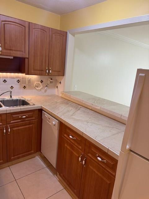 A kitchen features wood cabinets, a tiled countertop, a stainless steel sink, and a dishwasher — 9301 SW 92nd Ave # 210C, Miami FL 33176, MIAMI, FL
