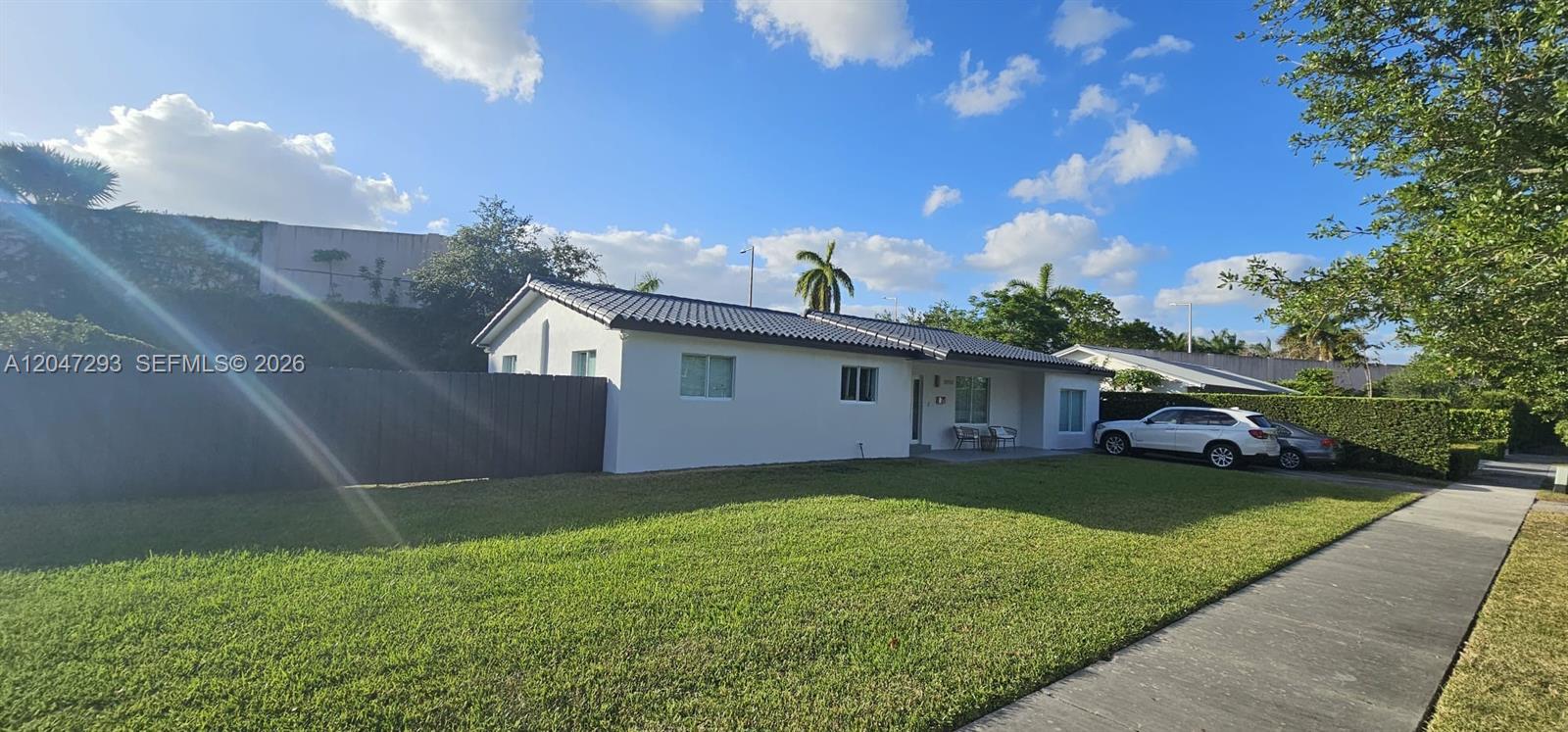 A single-story white house with a dark roof sits behind a large green lawn — 10900 SW 107th Ave, Miami FL 33176, MIAMI, FL