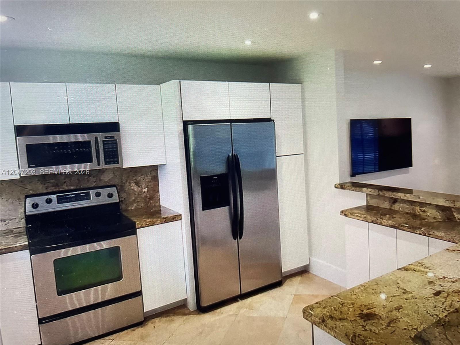A kitchen features white cabinets, stainless steel appliances, and brown granite countertops — 10900 SW 107th Ave, Miami FL 33176, MIAMI, FL