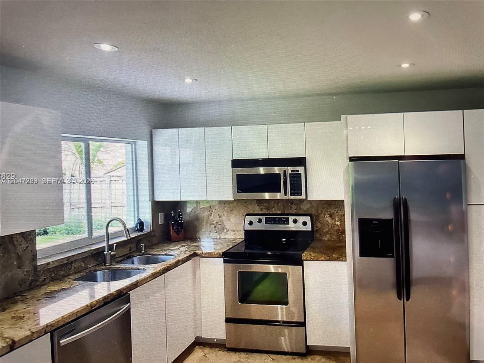 A kitchen features white cabinets, stainless steel appliances, and brown granite countertops — 10900 SW 107th Ave, Miami FL 33176, MIAMI, FL