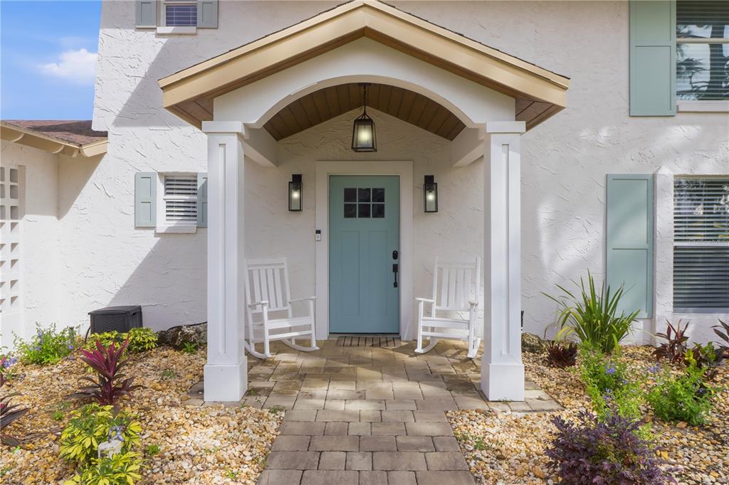 A light blue front door sits under a covered porch with two white rocking chairs — 9235 W HARBOR ISLE COURT, CRYSTAL RIVER, FL