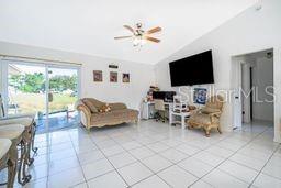 A bright living room features white tile floors, a vaulted ceiling, and a sliding glass door — 14 CEDAR TRACE TERRACE, OCALA, FL
