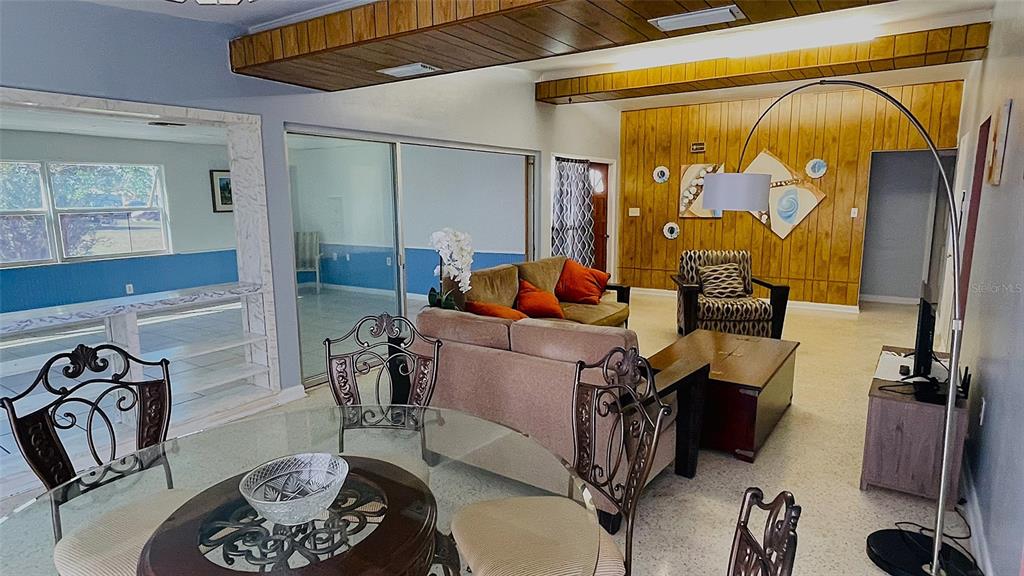 A living and dining area features wood-paneled walls, a drop ceiling, and tile flooring — 554 LINDLEY TERRACE, PORT CHARLOTTE, FL