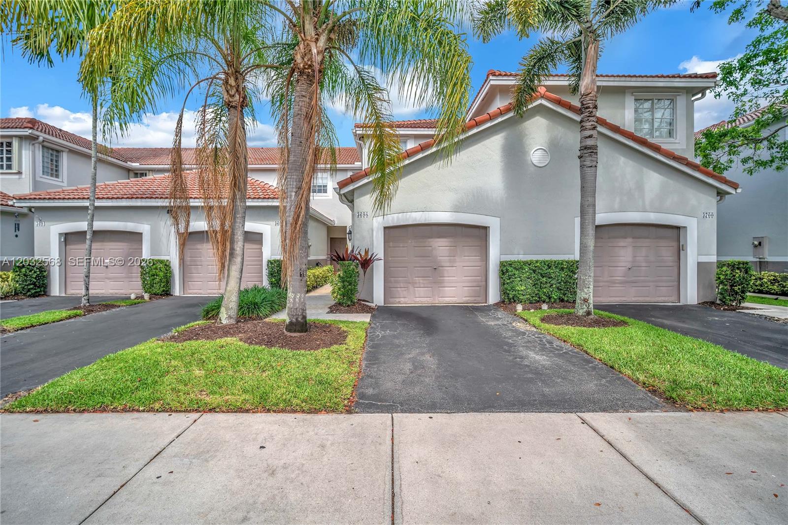 The exterior view shows a row of townhouses with beige stucco walls and tile roofs — 3698 San Simeon Cir, Weston FL 33331, WESTON, FL