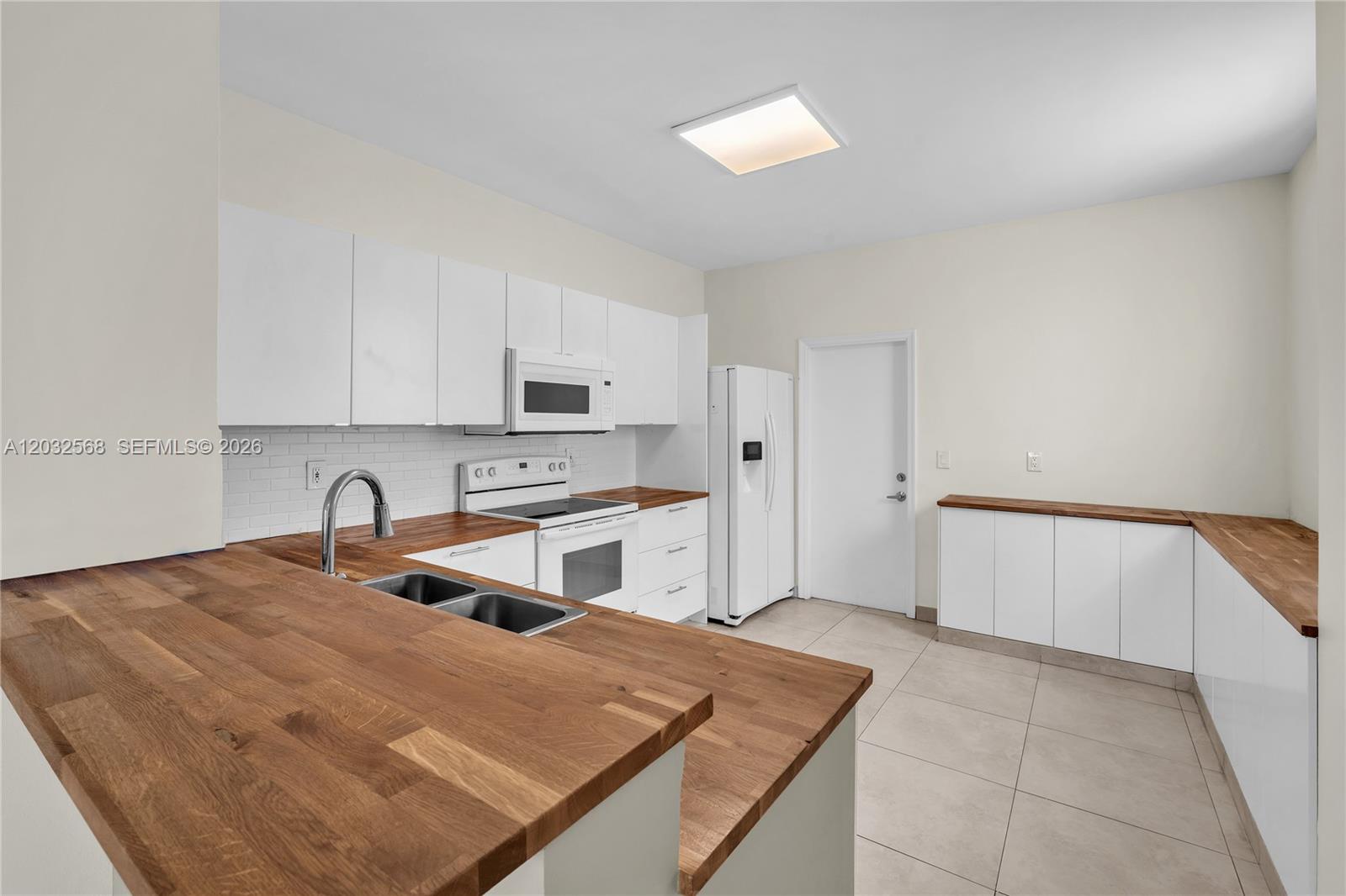 A kitchen features white cabinets, wood countertops, stainless steel appliances, and light tile flooring — 3698 San Simeon Cir, Weston FL 33331, WESTON, FL