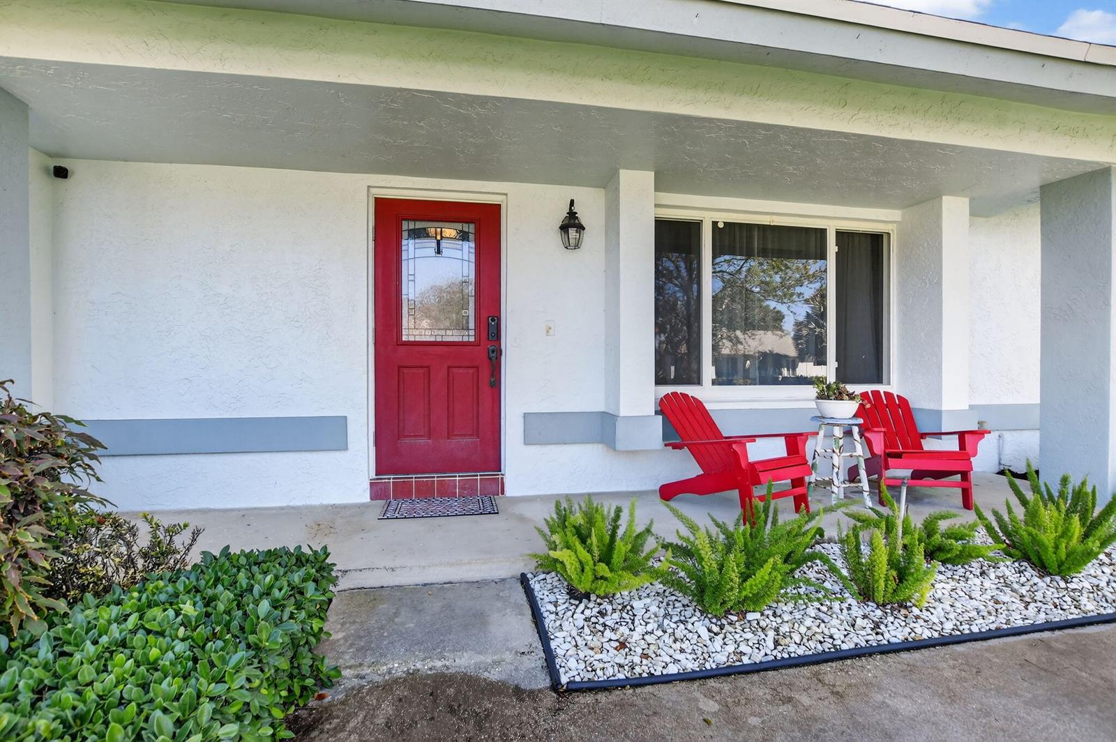 A red front door and two red chairs sit on a covered porch — 18298 102nd Way, Boca Raton FL 33498, BOCA RATON, FL