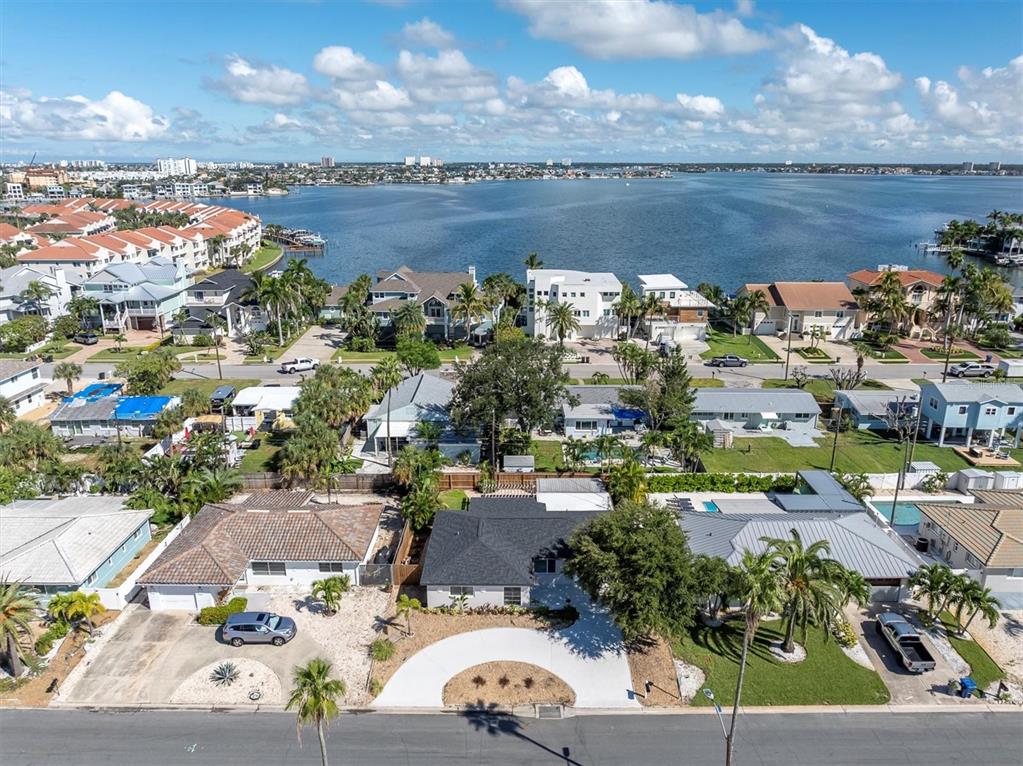 An aerial view shows a residential neighborhood with houses, palm trees, and a large bay — 197 LIDO DRIVE, ST PETE BEACH, FL