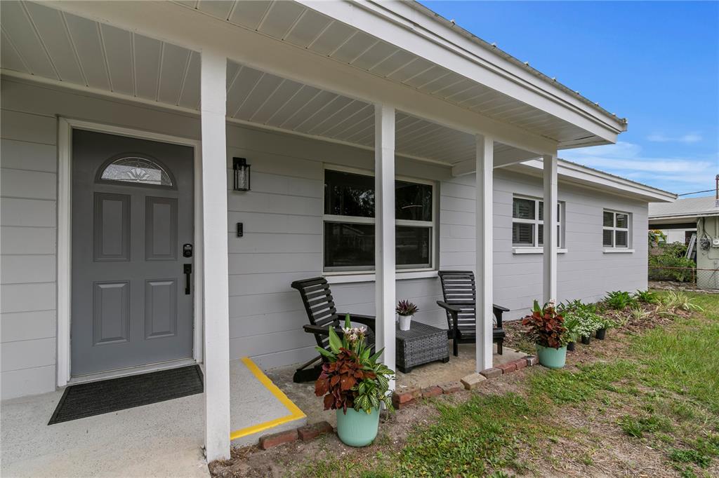A gray house exterior features a covered front porch with chairs and potted plants — 2910 W PRICE AVENUE, TAMPA, FL