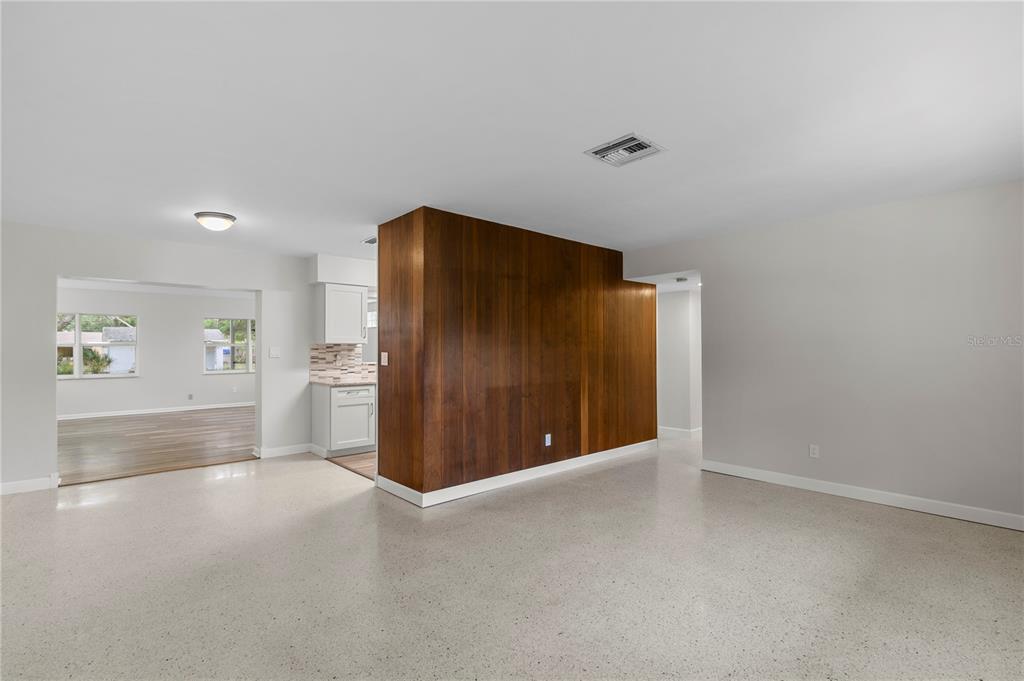 An open living area features a central wood-paneled wall and light-colored terrazzo flooring — 2910 W PRICE AVENUE, TAMPA, FL