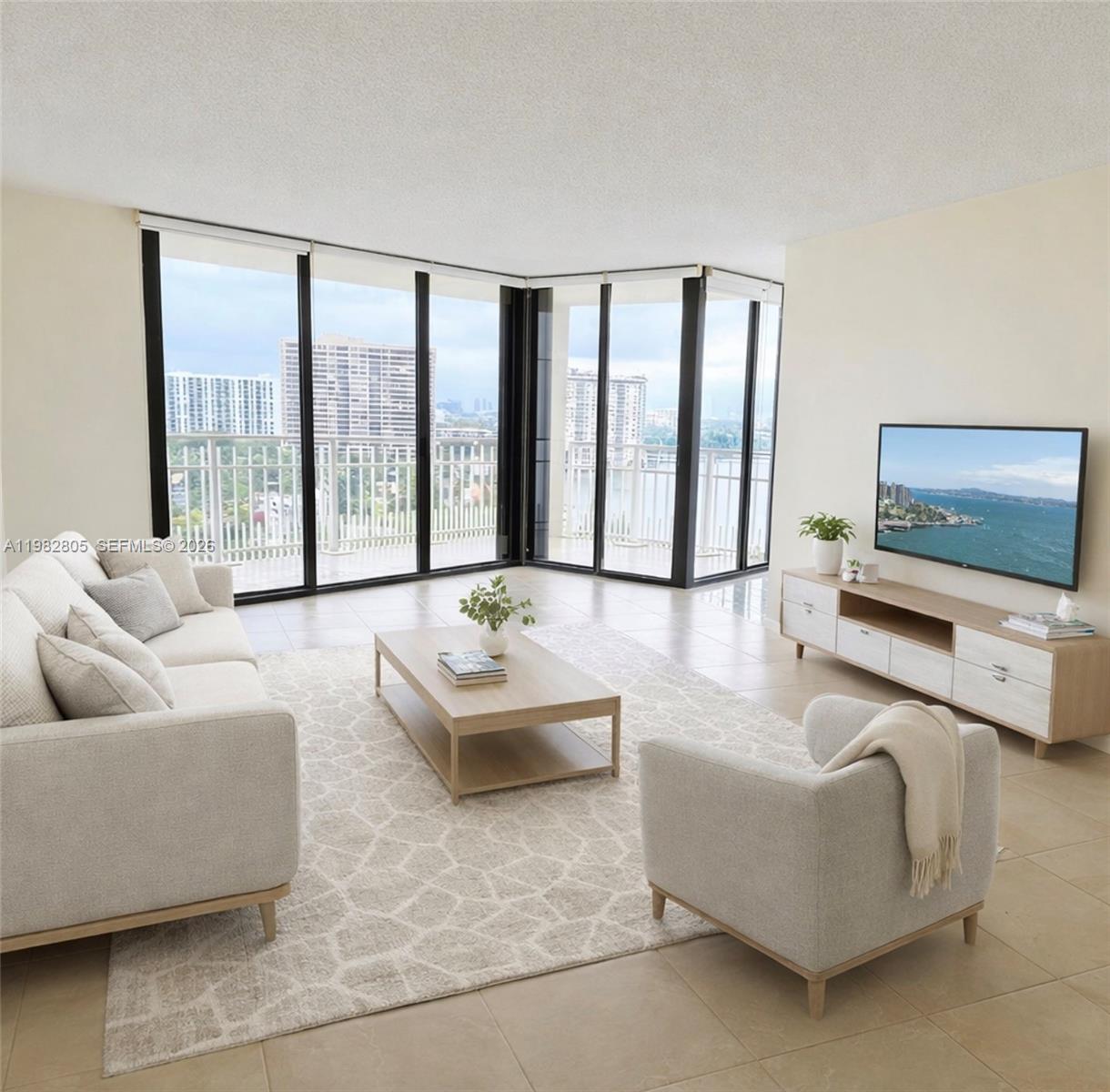 A living room with light furniture, a patterned rug, and floor-to-ceiling windows overlooking a city — 4000 Towerside Ter # 1401, Miami FL 33138, MIAMI, FL