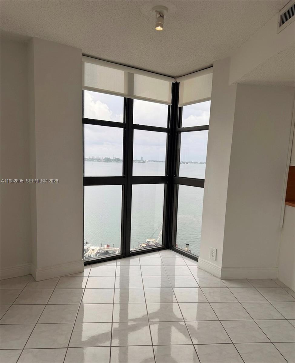 A room with white tile floors and floor-to-ceiling corner windows overlooking a body of water — 4000 Towerside Ter # 1401, Miami FL 33138, MIAMI, FL